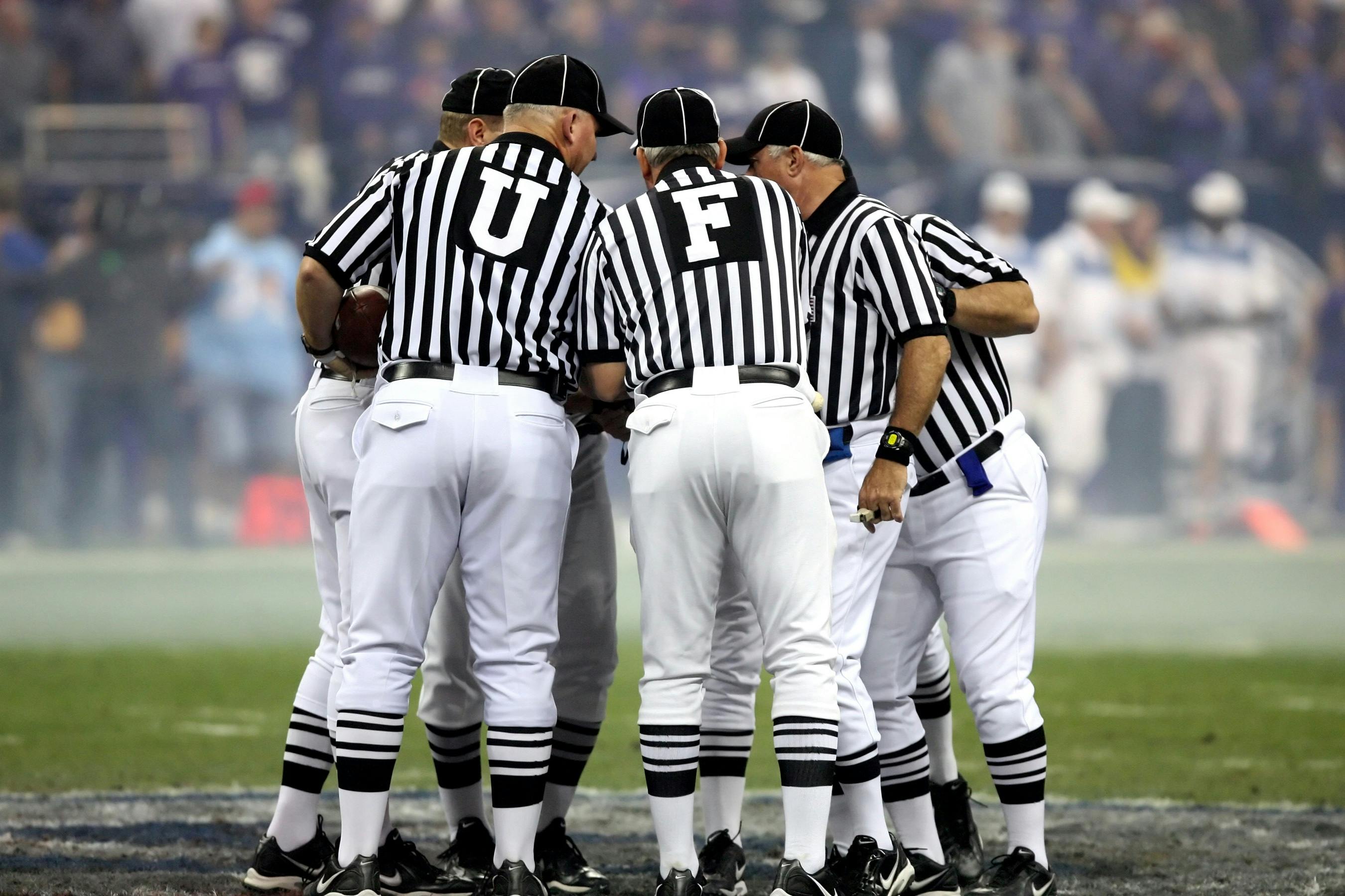 Football officials in team huddle demonstrating teamwork and collaboration